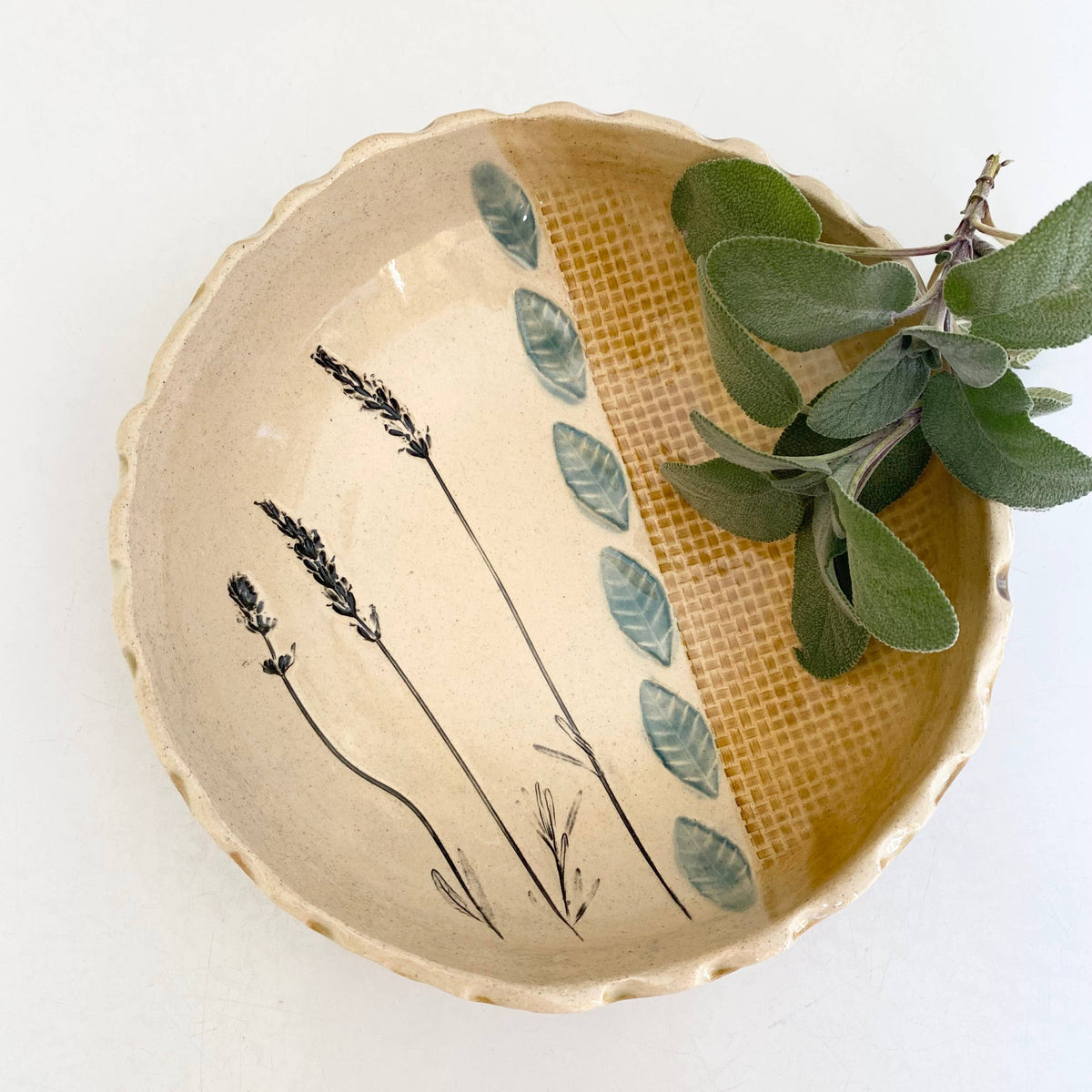 Ceramic bowl with botanical design and green leaves on a white background