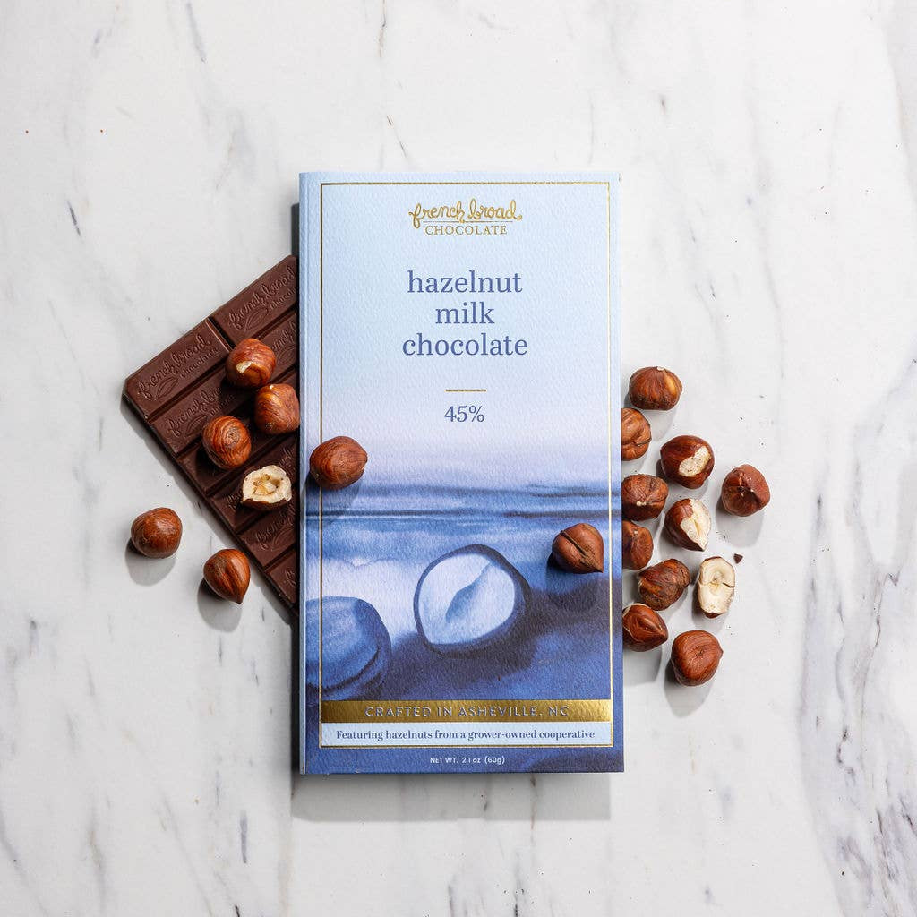 Chocolate bar and packaging with hazelnuts on a marble surface