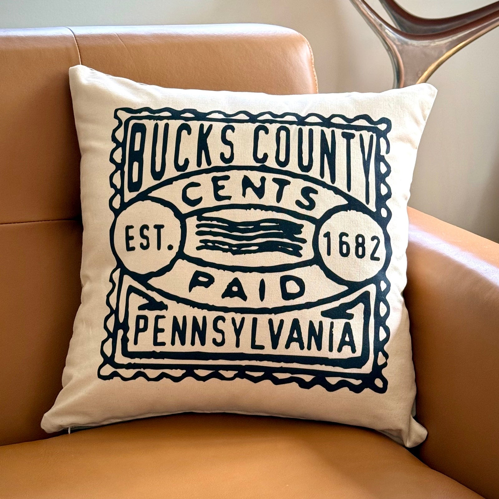 Decorative pillow with 'Bucks County, Pennsylvania' text on a brown couch.