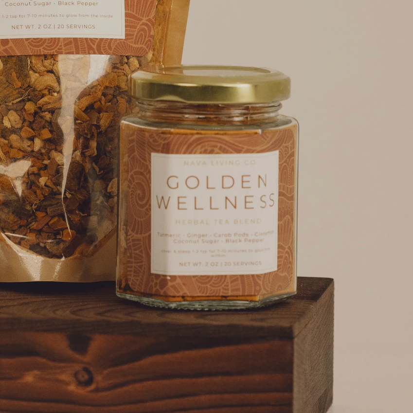 Jar of 'Golden Wellness' herbal tea on a wooden block with a beige background