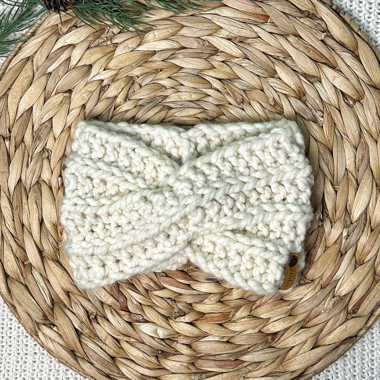 Knitted headband on a woven mat with greenery