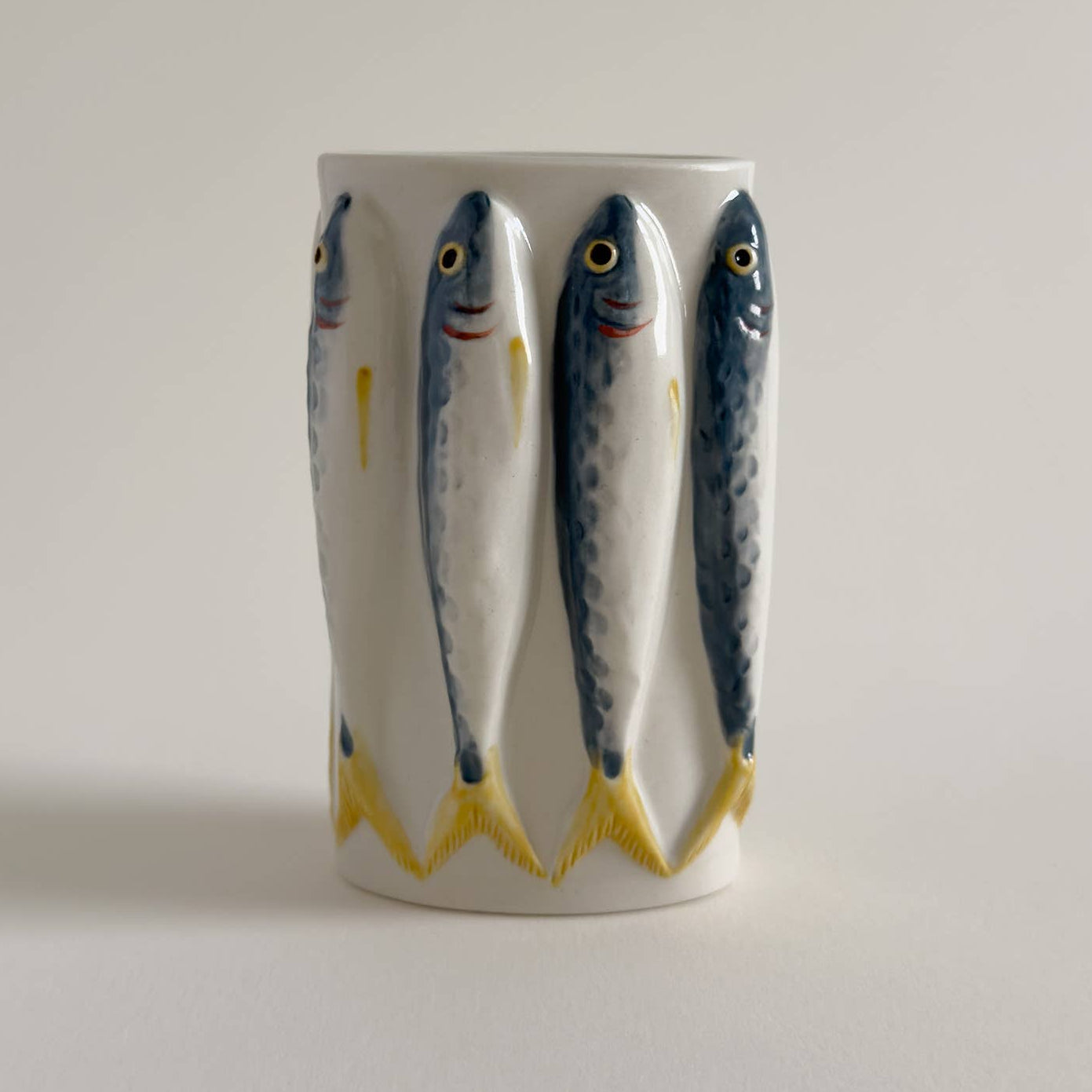 Porcelain fish vase with fish design on a plain background