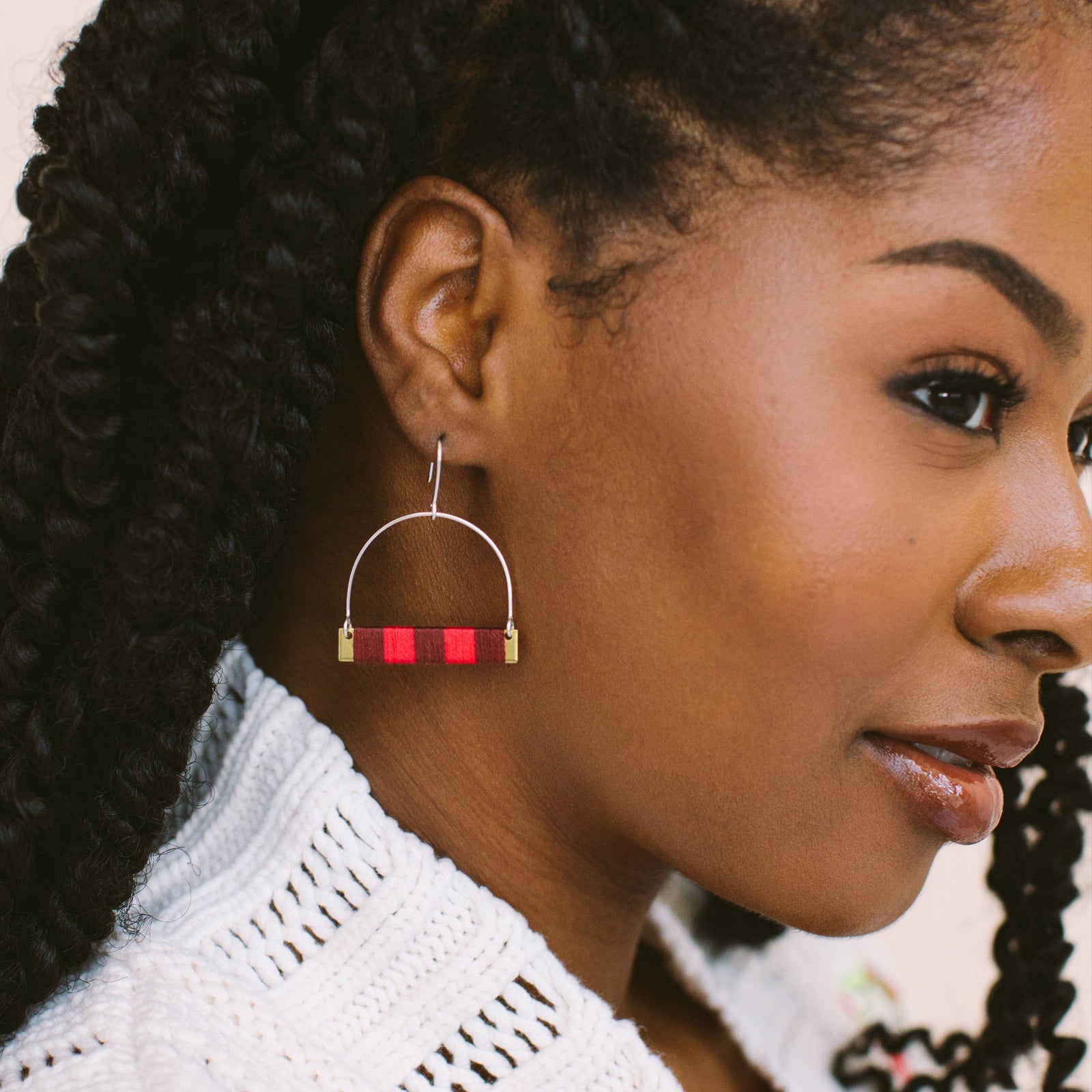 Woman wearing a white crochet top with floral patterns, showcasing an earring.