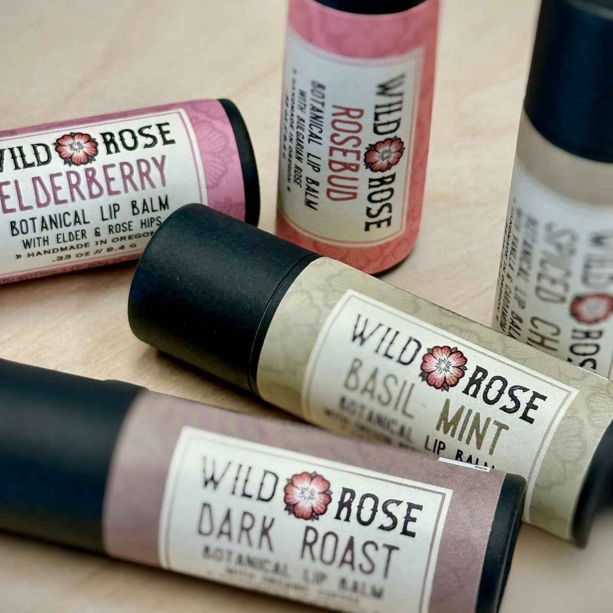 Roll-on lip balms from Wild Rose with visible labels on a wooden surface
