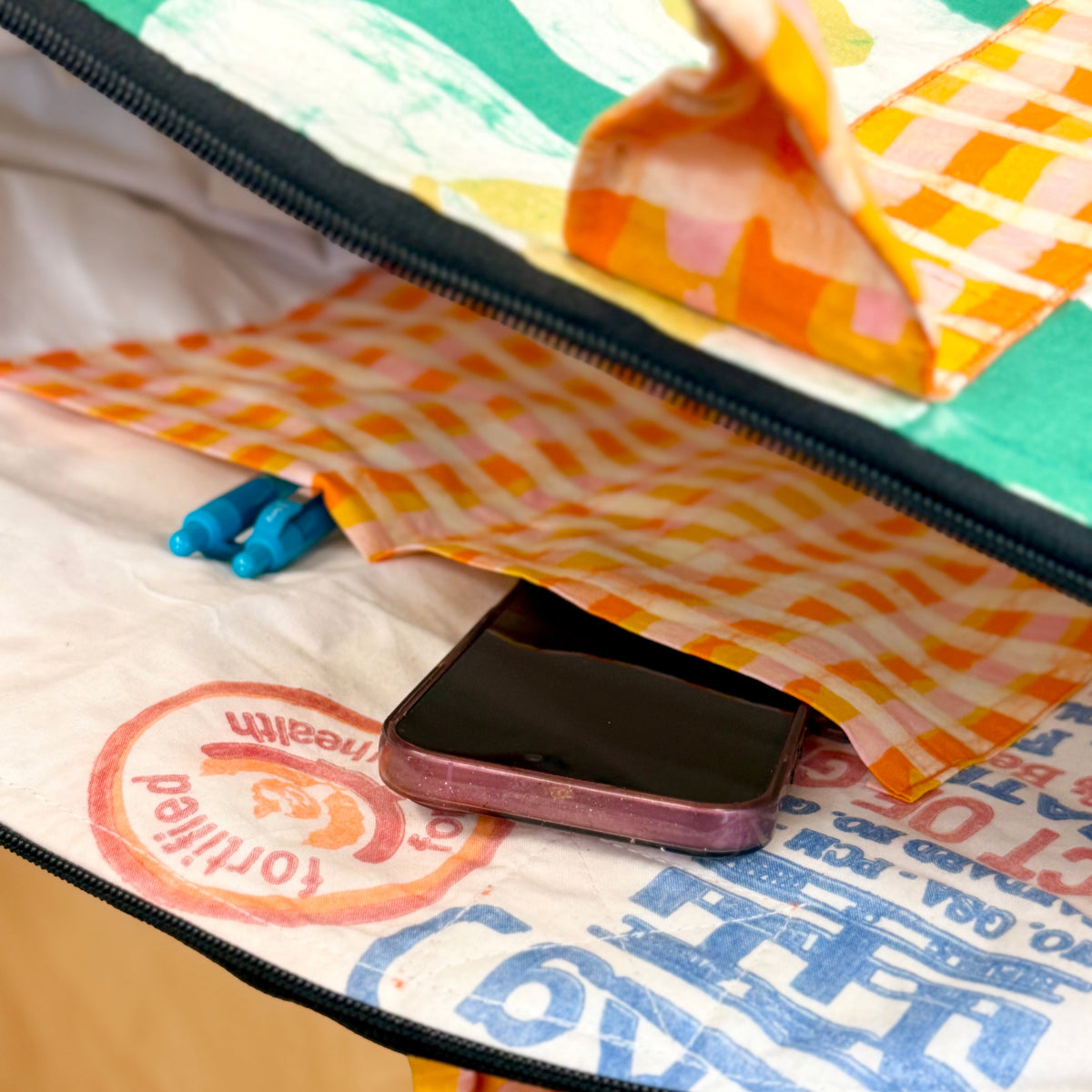 Phone inside a colorful bag with visible brand logos