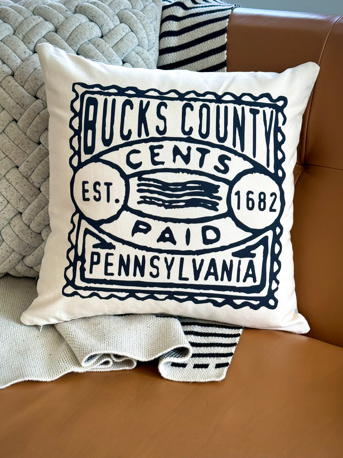 Decorative pillow with 'Bucks County Cents' text on a couch