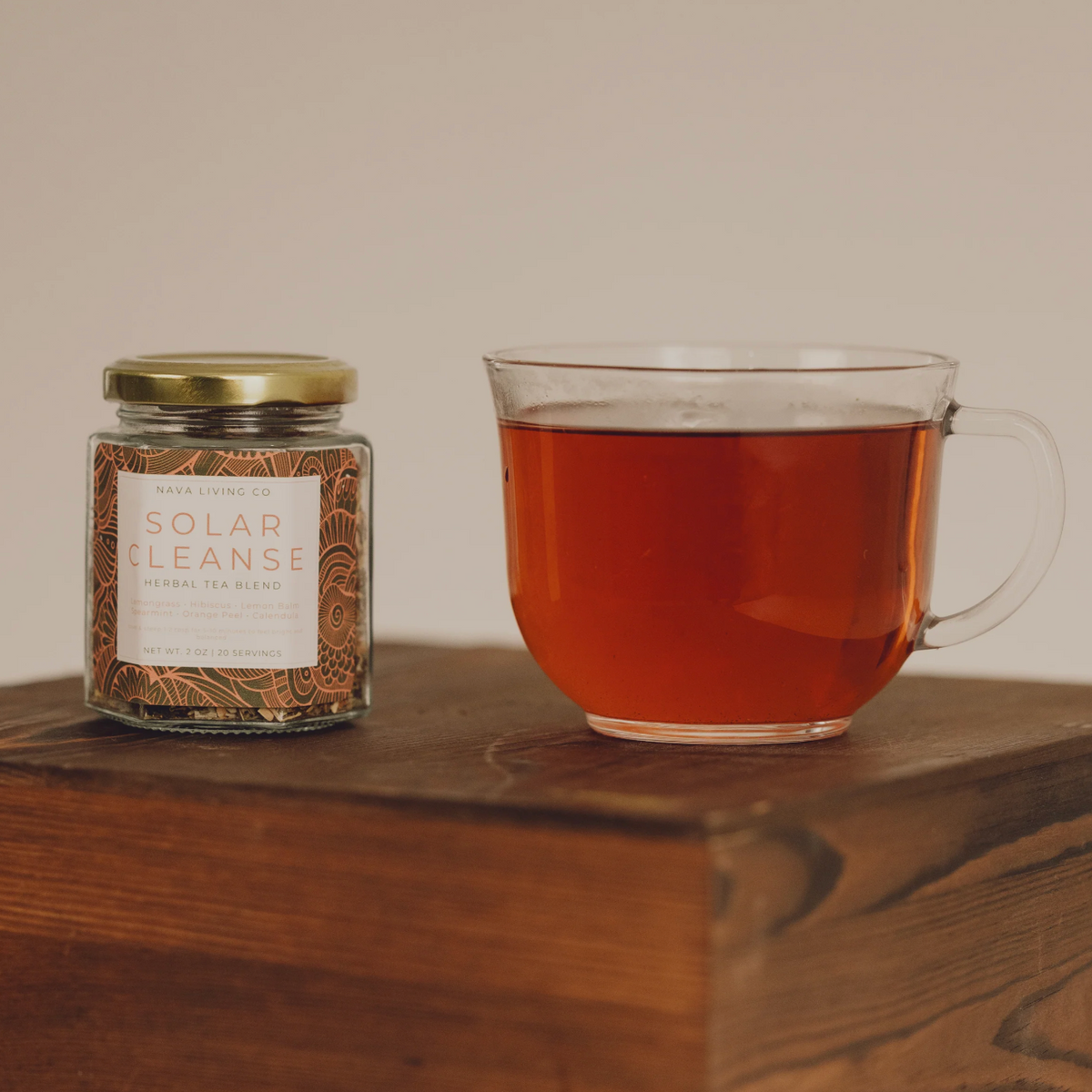 Jar of 'Solar Cleanse' herbal tea blend and a glass mug of tea on a wooden surface.