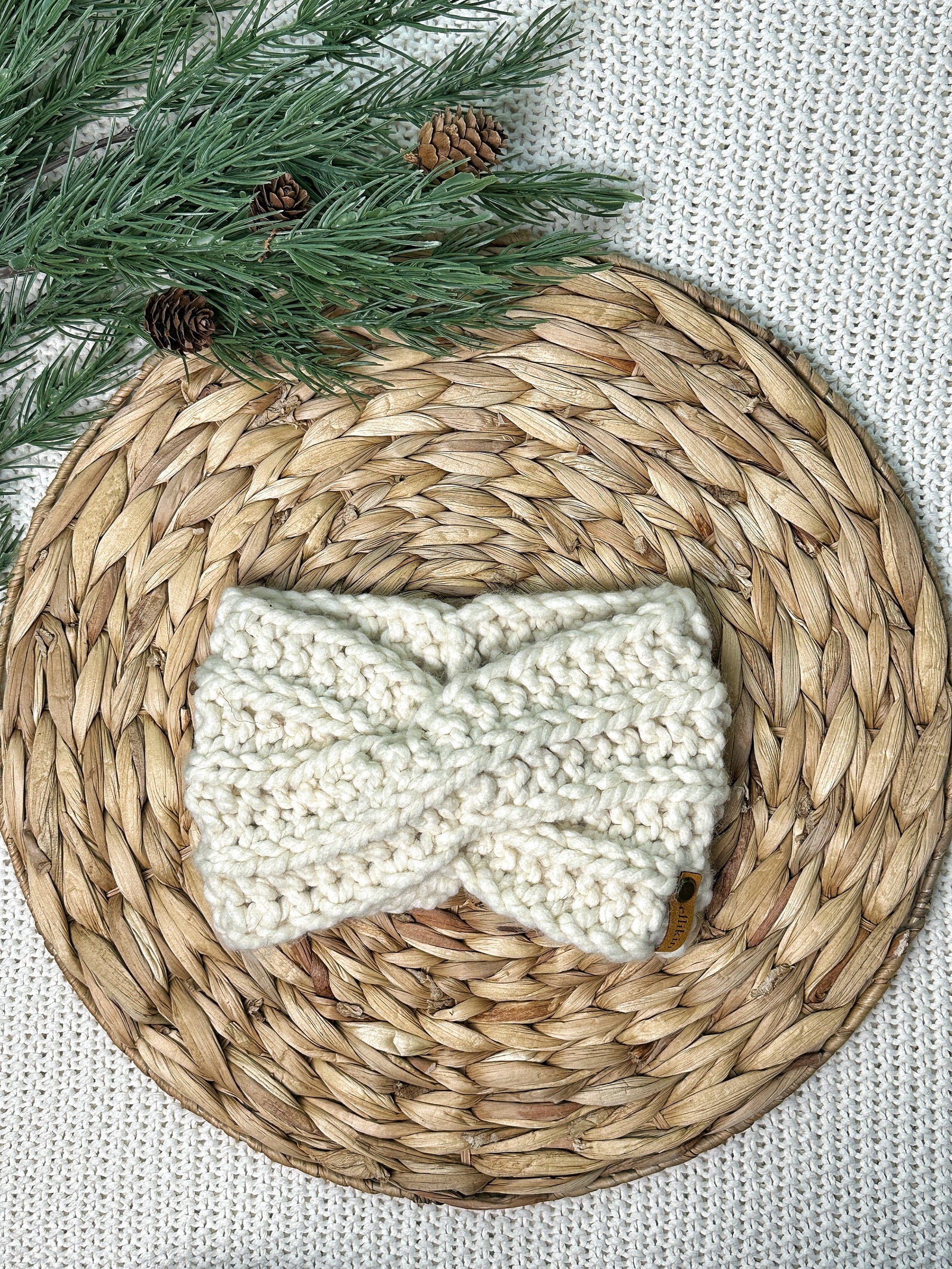 Knitted headband on a woven mat with greenery