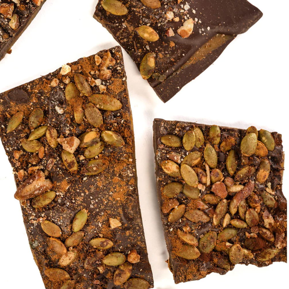 Chocolate toffee bars with pumpkin spice and pepita seed toppings on a white background